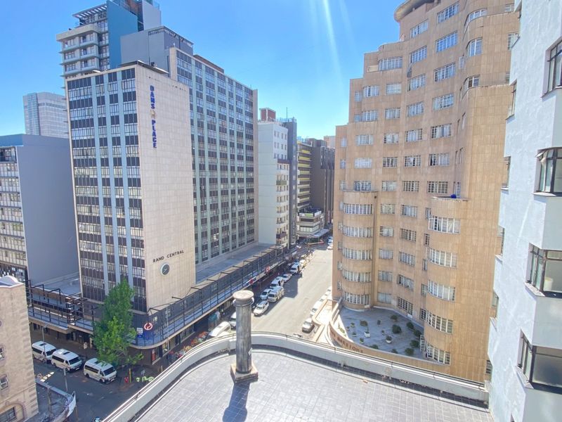 An elevated urban view overlooking surrounding city buildings and street level activity from an apartment perspective.