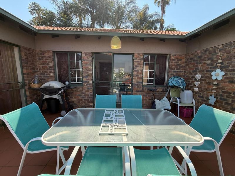 A covered outdoor patio area featuring exposed brick walls, tiled flooring, and direct access to the interior through sliding glass doors.