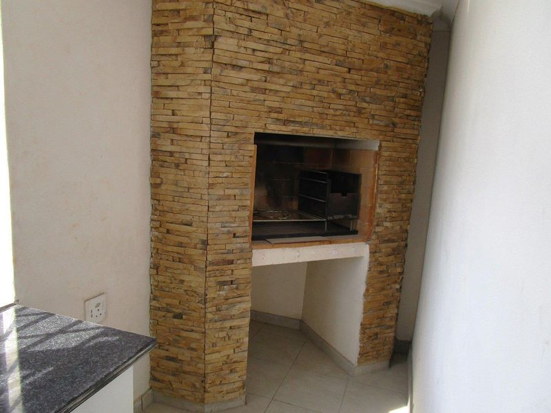 A built-in braai area featuring stone cladding, a granite countertop, and tiled flooring, suitable for outdoor entertainment.