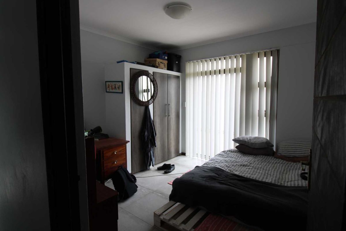 A bedroom featuring built-in cupboards and vertical blinds, providing functional storage and adjustable natural light control.
