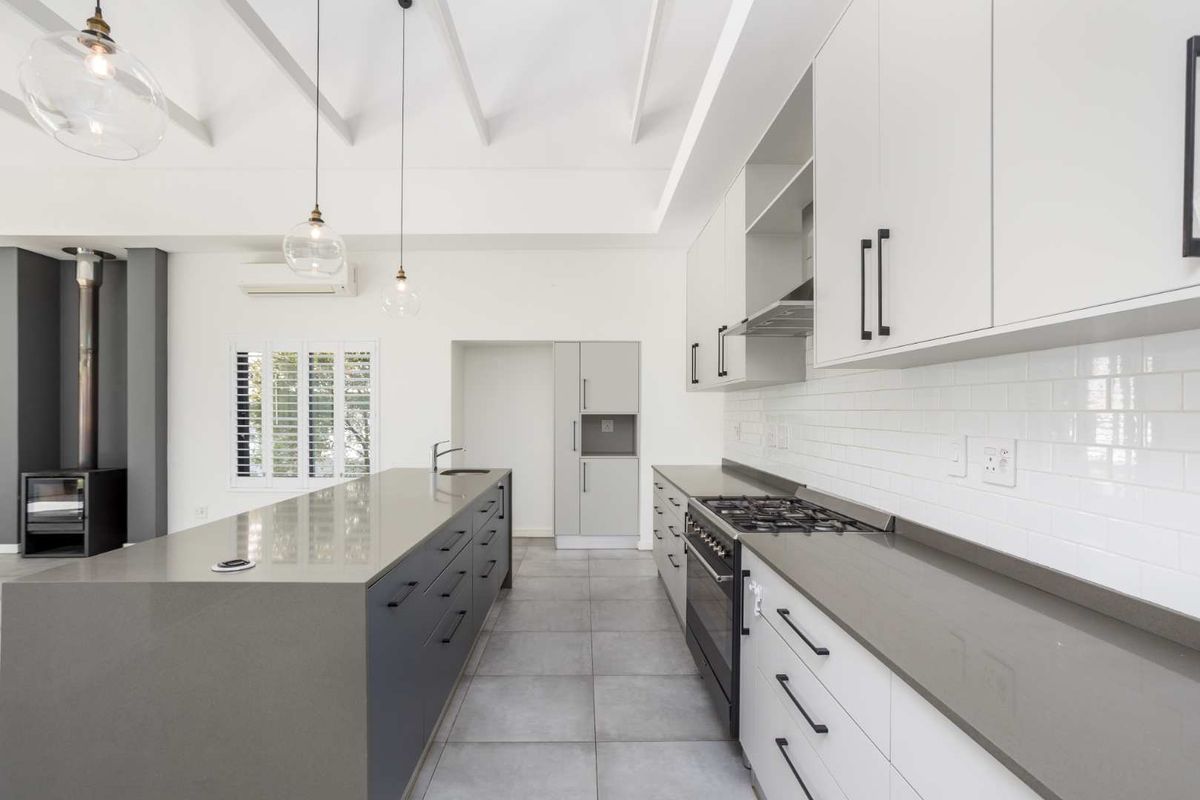 Modern kitchen featuring a large island, quartz countertops, subway tile backsplash, gas cooktop, and an integrated wood-burning fireplace in an open-plan layout.