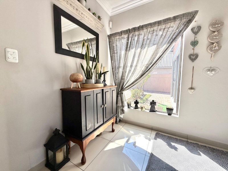 A bright entrance area featuring polished floor tiles, decorative crown molding, and a large window providing natural light.