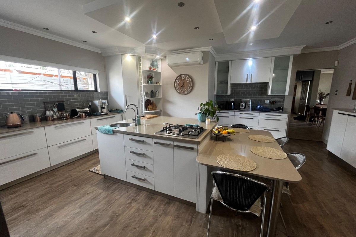 Modern kitchen featuring white cabinetry, stone countertops, a central island with a built-in gas hob, and a subway tile backsplash.