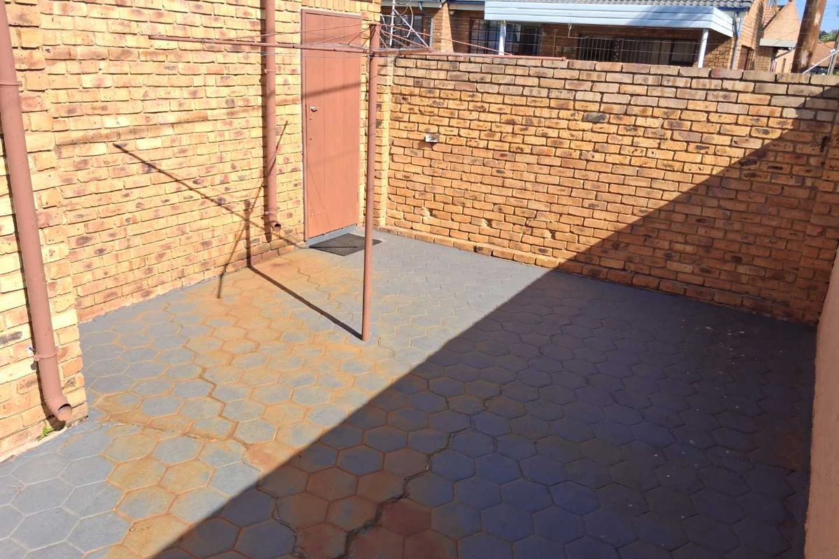 A private rear courtyard area featuring brick boundary walls, paved flooring, and a fixed rotary washing line.