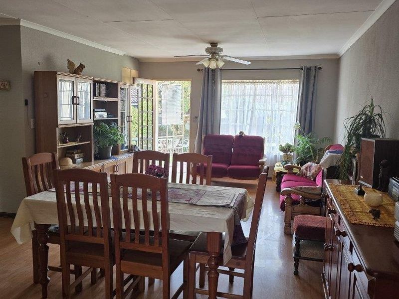 Open-plan living and dining area featuring laminate flooring, a ceiling fan, and direct access to an outdoor patio through a sliding glass door.