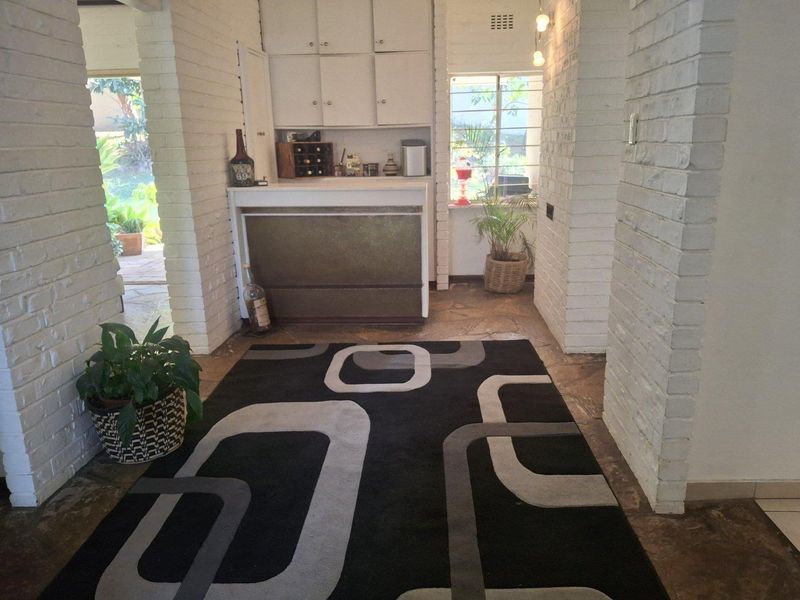 A dedicated bar area featuring built-in cabinetry, a service counter, and rustic exposed brick columns with stone flooring.