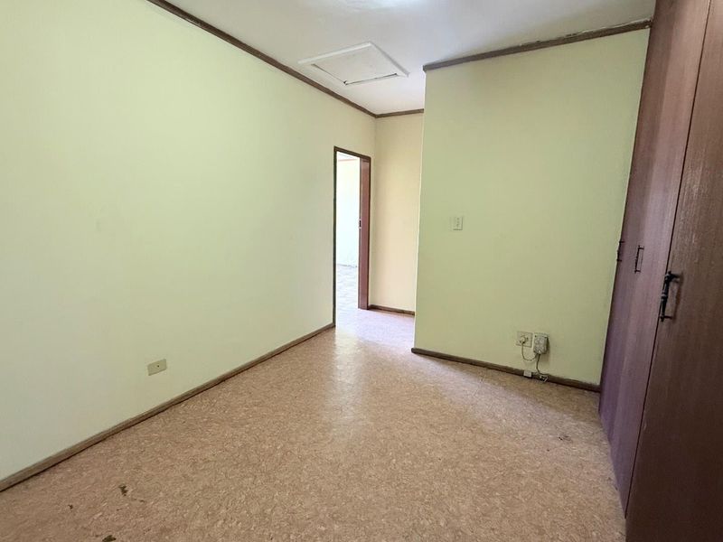 An empty office space featuring built-in cupboards, neutral walls, and durable flooring, offering a functional layout for a professional workspace.