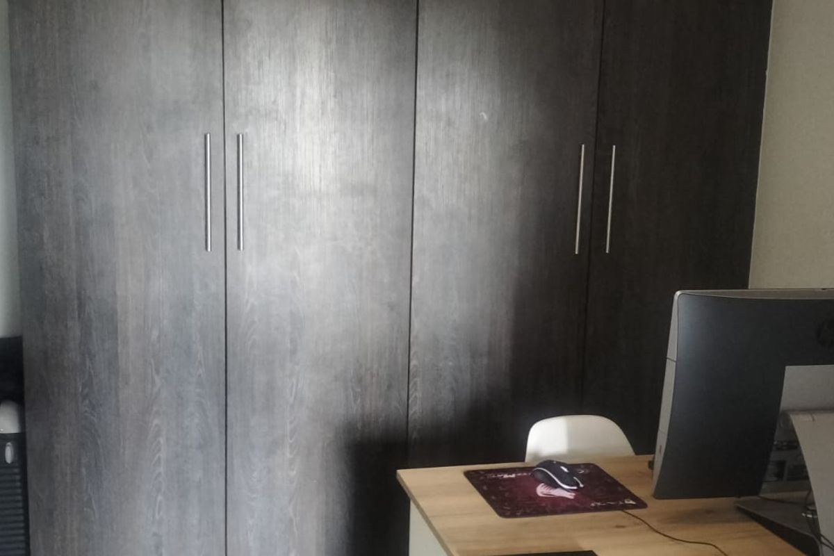A bedroom featuring dark wood-finish built-in cupboards providing ample storage space.