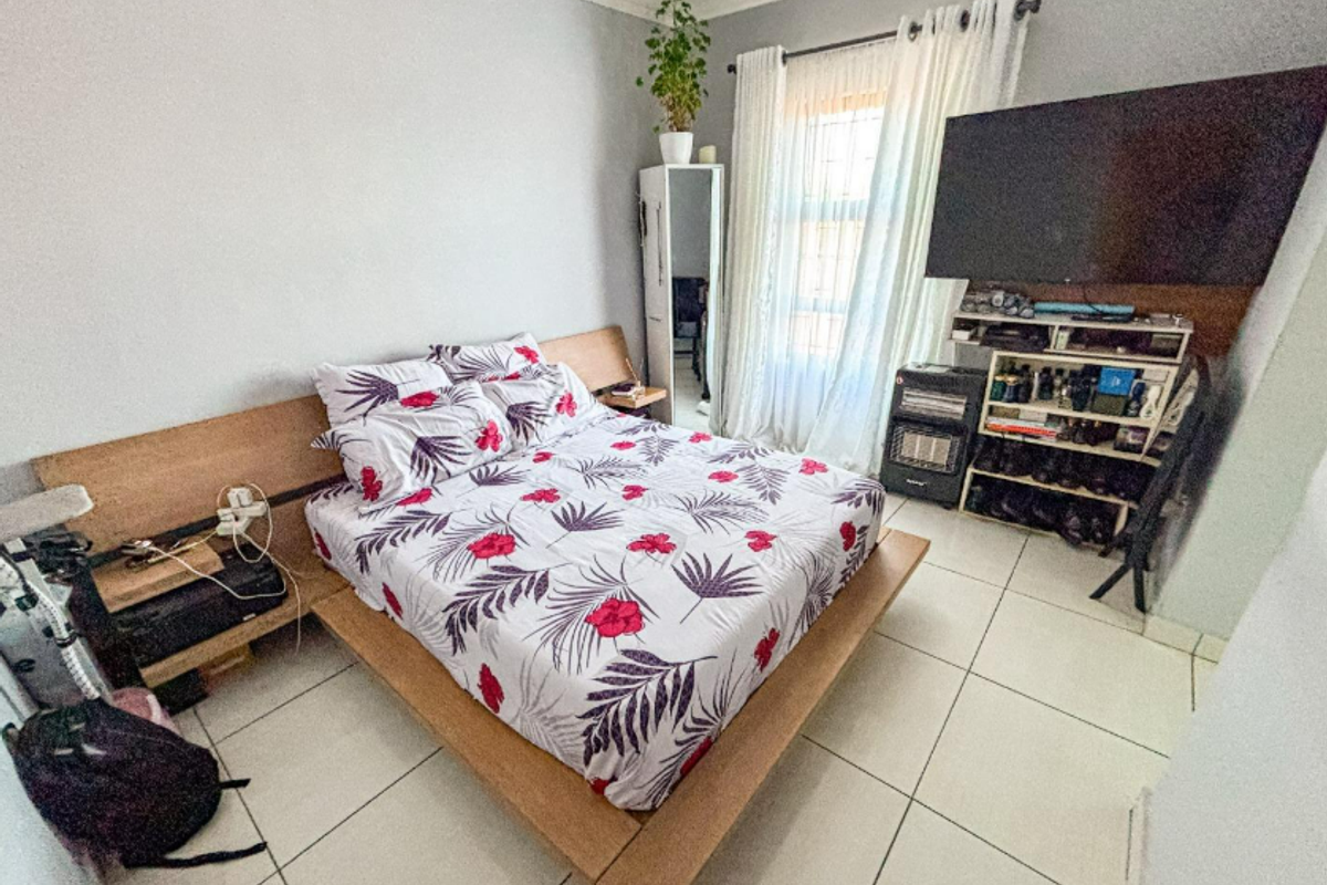 A functional bedroom featuring tiled flooring and a built-in wooden headboard, offering a neutral base for personalization.