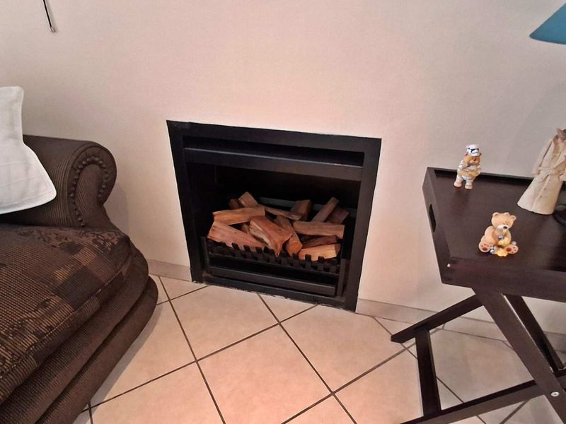 A living room area featuring a built-in fireplace with a black metal surround and tiled flooring.