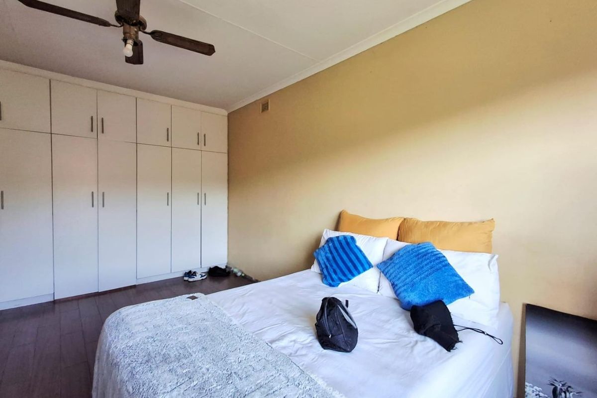 A bedroom featuring built-in cupboards and a ceiling fan, providing functional storage and climate control.