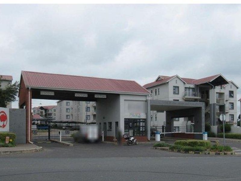The main entrance and security gatehouse of the apartment complex, featuring controlled access points and well-maintained building exteriors.