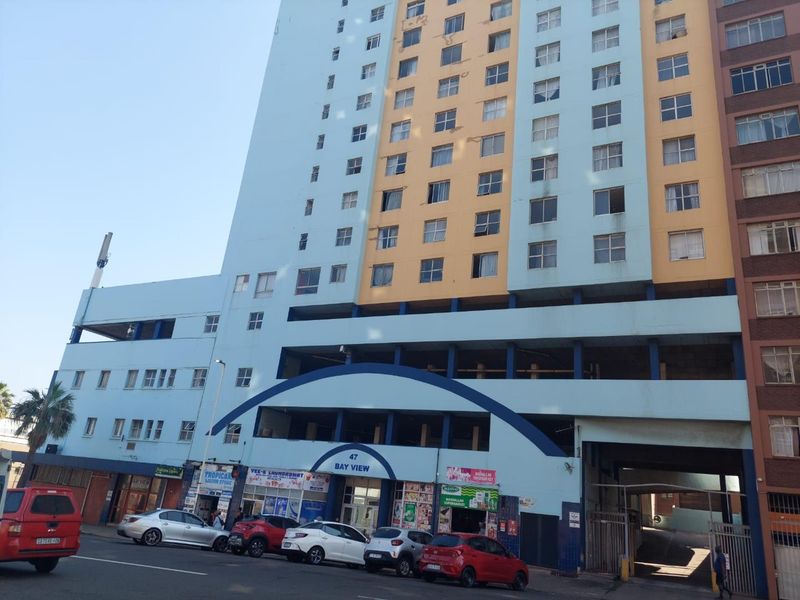 Exterior view of the Bay View apartment building featuring a multi-story facade with ground-level retail spaces and integrated parking.