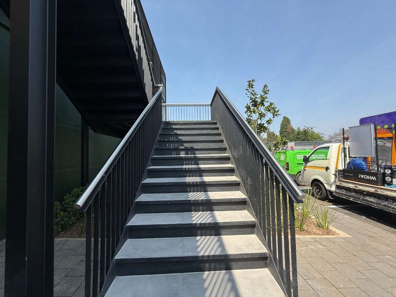 An exterior view of a modern metal staircase providing access to the upper level of the retail property.