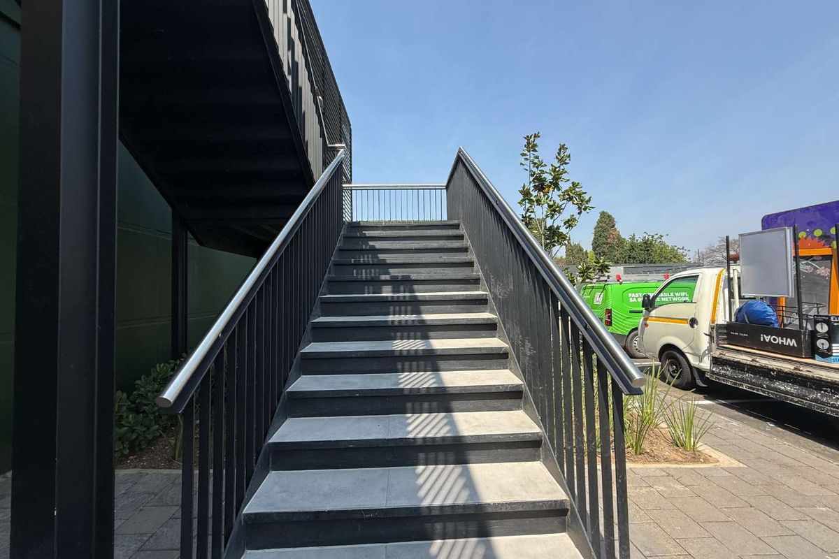 An exterior view of a modern metal staircase providing access to the upper level of the retail property.