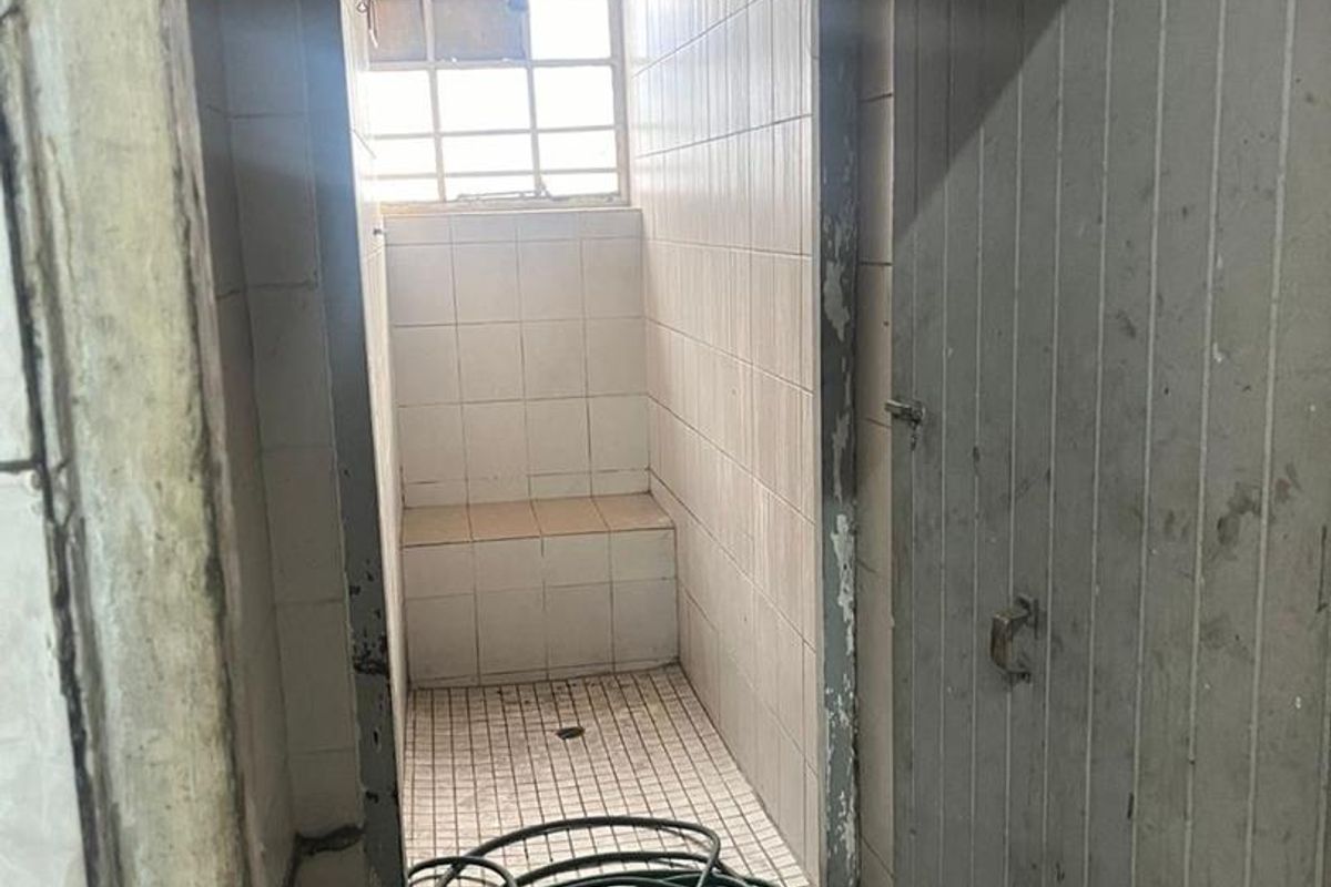 A small, dated shower room featuring a built-in tiled bench and shower area, requiring refurbishment to improve its condition and functionality.