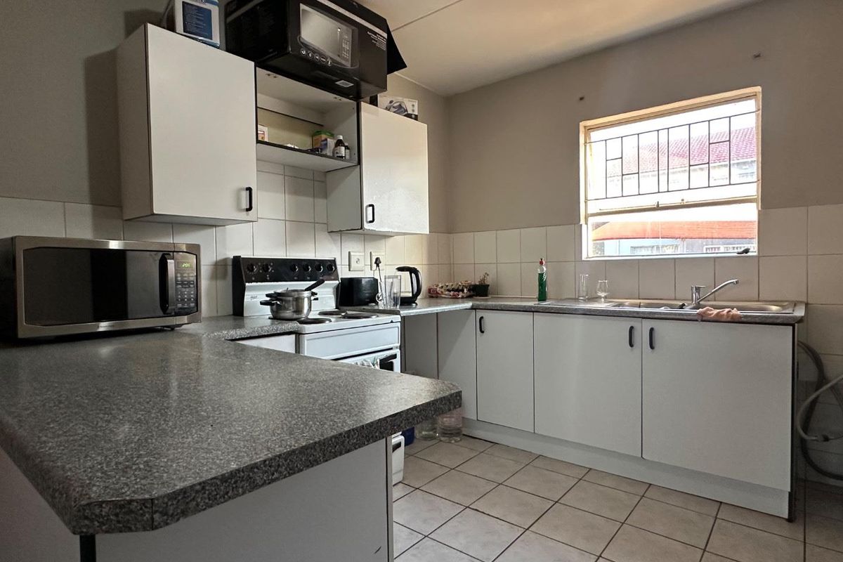 Functional kitchen featuring white cabinetry, laminate countertops, tiled splashbacks, and a built-in stove with extractor fan.