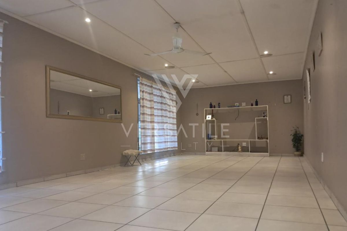 Spacious living area featuring neutral tiled flooring, recessed downlighting, and a ceiling fan, offering a versatile open-plan layout.