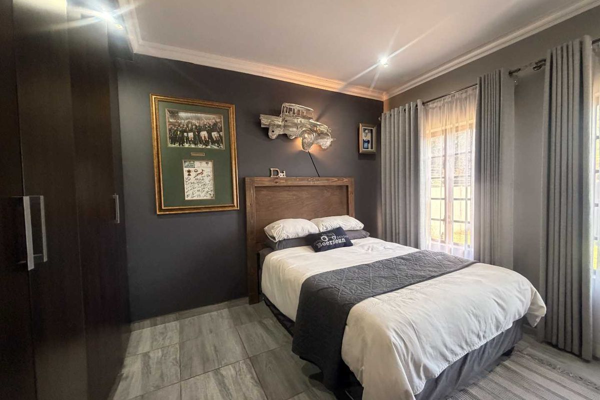 A well-maintained bedroom featuring dark grey feature walls, tiled flooring, built-in cupboards, and recessed downlighting.