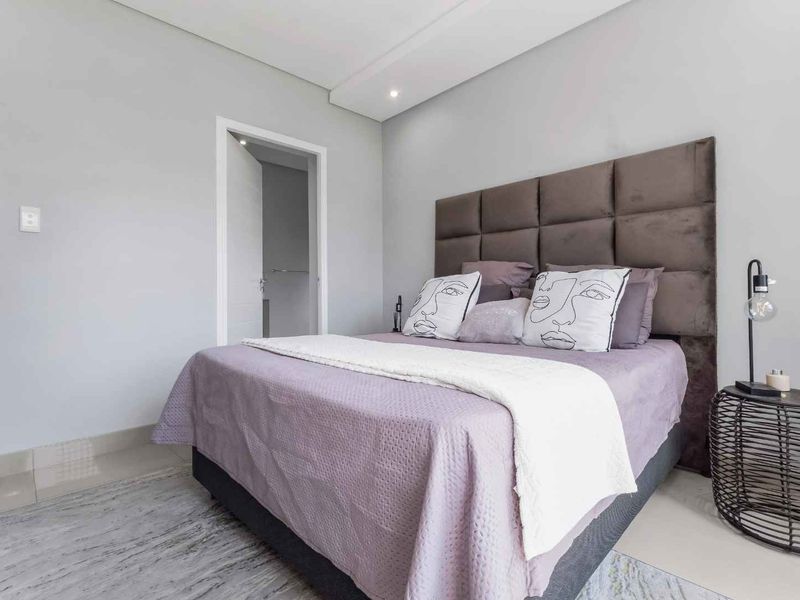 A well-maintained bedroom featuring neutral wall tones, recessed ceiling lighting, and tiled flooring, providing a clean and modern living space.