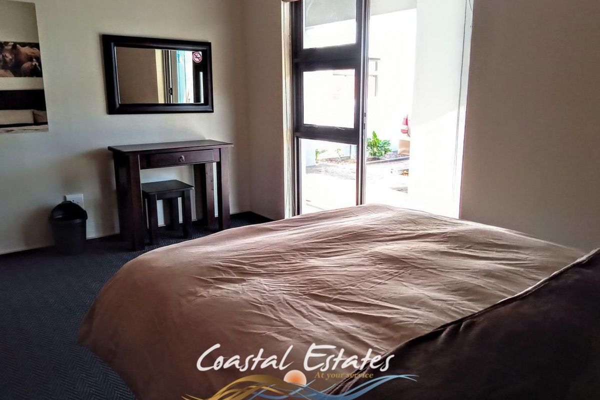 A comfortable bedroom featuring carpeted flooring, a built-in vanity area, and a sliding glass door providing direct access to the exterior.