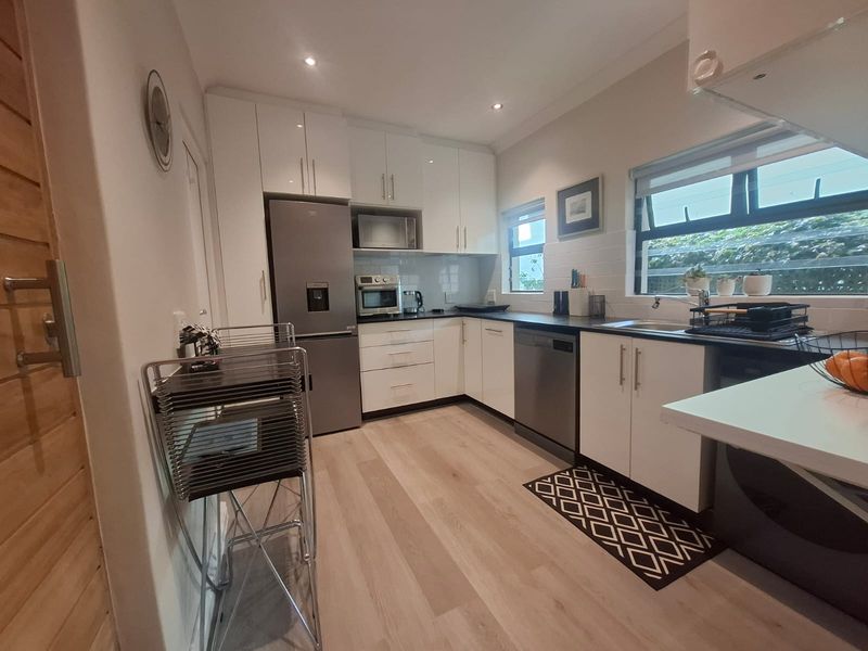 Modern kitchen featuring white cabinetry, laminate countertops, stainless steel appliances, recessed lighting, and light-toned laminate flooring.