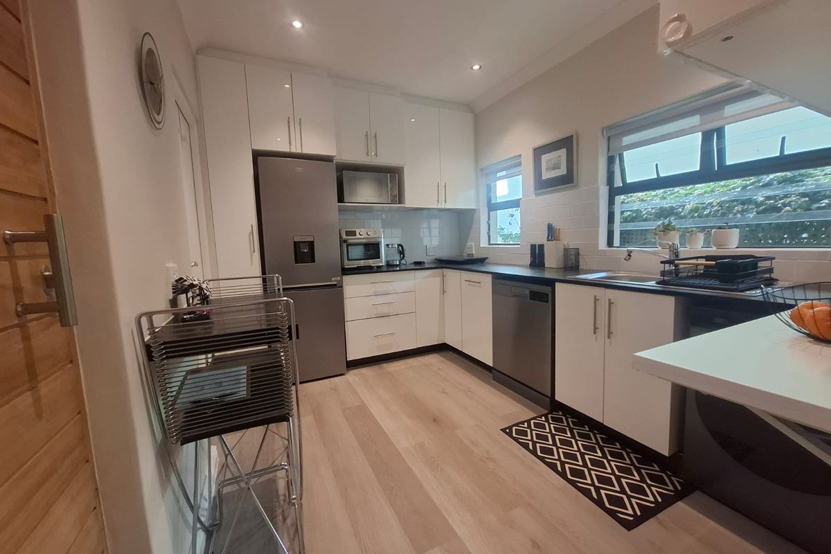 Modern kitchen featuring white cabinetry, laminate countertops, stainless steel appliances, recessed lighting, and light-toned laminate flooring.