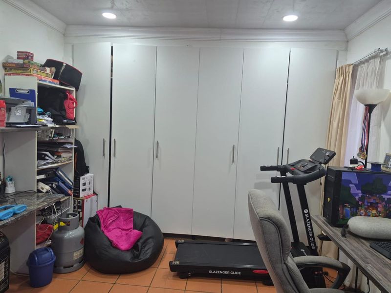 Bedroom featuring extensive built-in cupboards, tiled flooring, and recessed ceiling lighting.