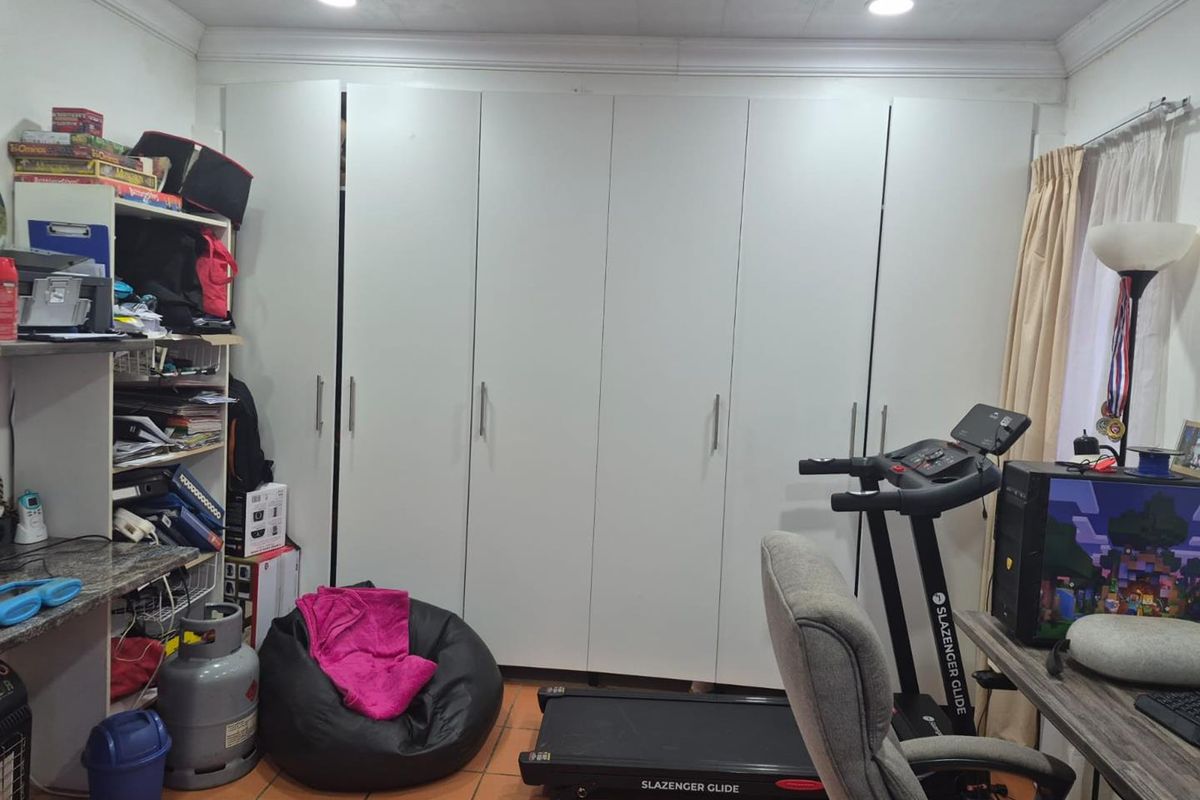 Bedroom featuring extensive built-in cupboards, tiled flooring, and recessed ceiling lighting.