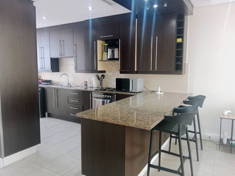 Modern kitchen featuring dark wood cabinetry, granite countertops, a breakfast bar, and integrated appliances, offering a functional and stylish cooking space.