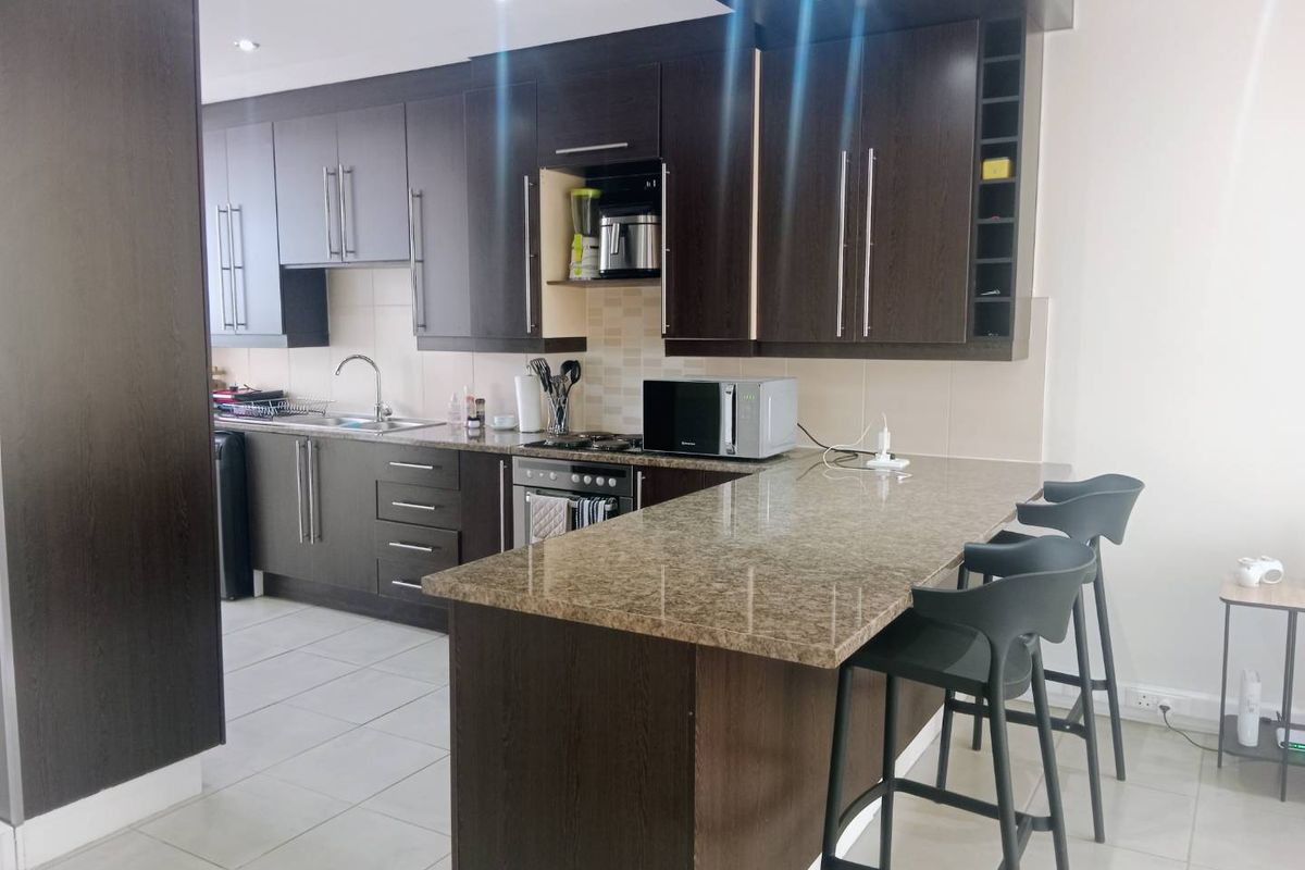 Modern kitchen featuring dark wood cabinetry, granite countertops, a breakfast bar, and integrated appliances, offering a functional and stylish cooking space.
