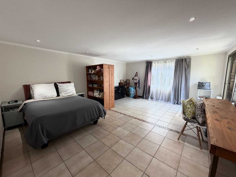 Spacious bedroom featuring neutral tiled flooring, recessed downlighting, and a large sliding glass door providing natural light.
