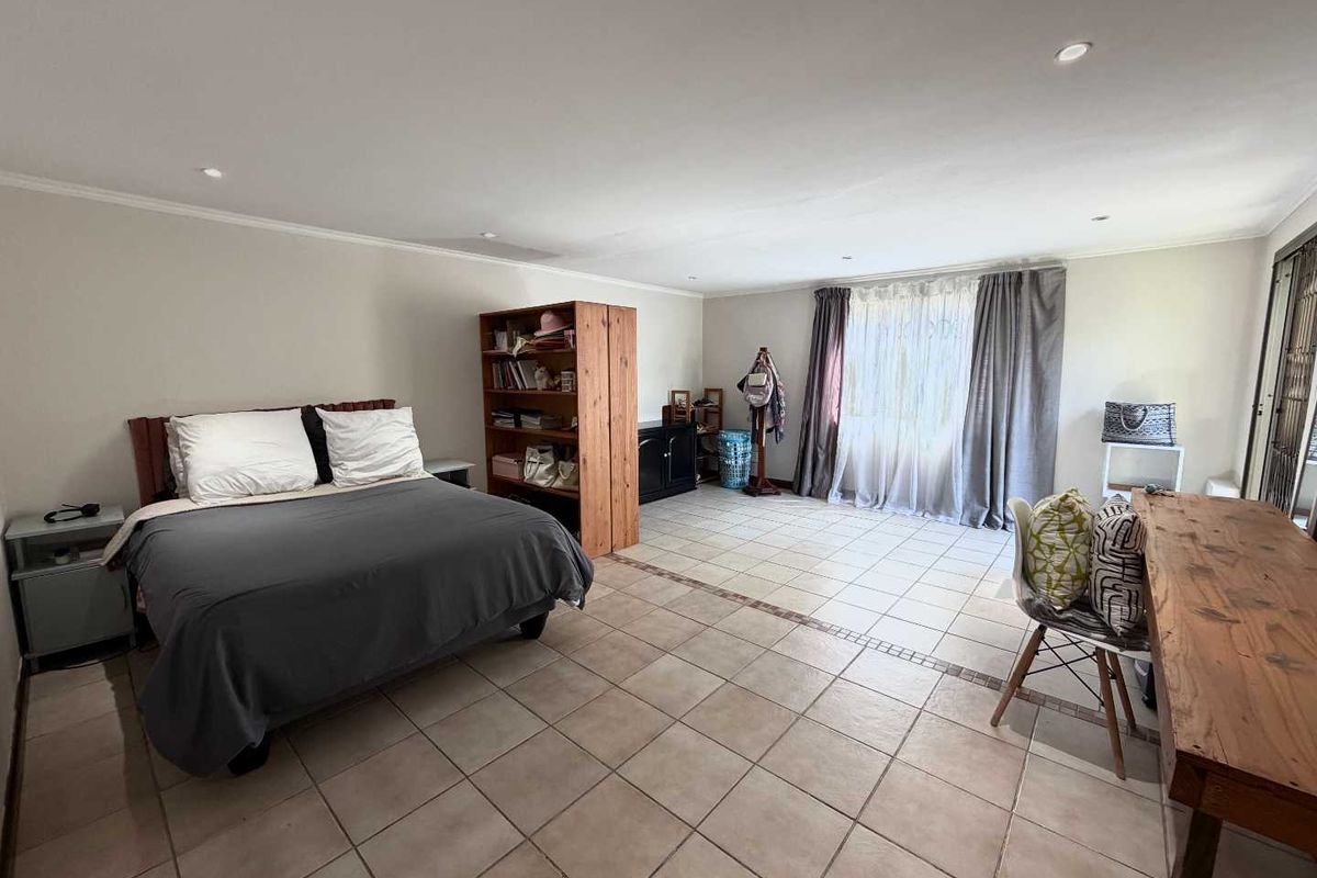 Spacious bedroom featuring neutral tiled flooring, recessed downlighting, and a large sliding glass door providing natural light.