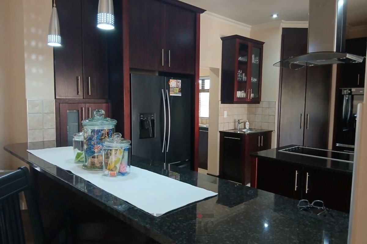 A well-appointed kitchen featuring dark wood cabinetry, granite countertops, a breakfast bar, and a stainless steel extractor fan.