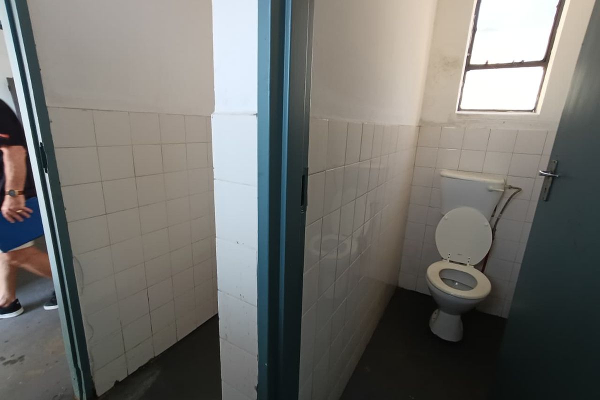 Functional industrial bathroom facility featuring tiled walls and a standard toilet unit, requiring cosmetic updates to improve overall condition.