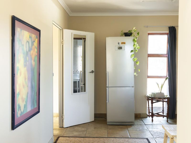 A functional hallway area featuring tiled flooring, coved ceilings, and a window providing natural light, leading into an adjacent room.