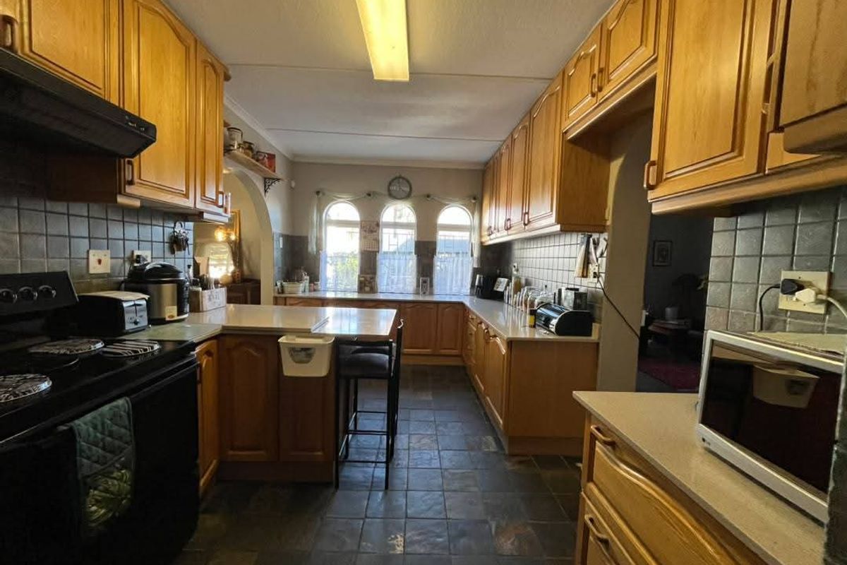 A traditional kitchen featuring wooden cabinetry, tiled backsplash, stone countertops, and a functional layout with an integrated oven and extractor fan.