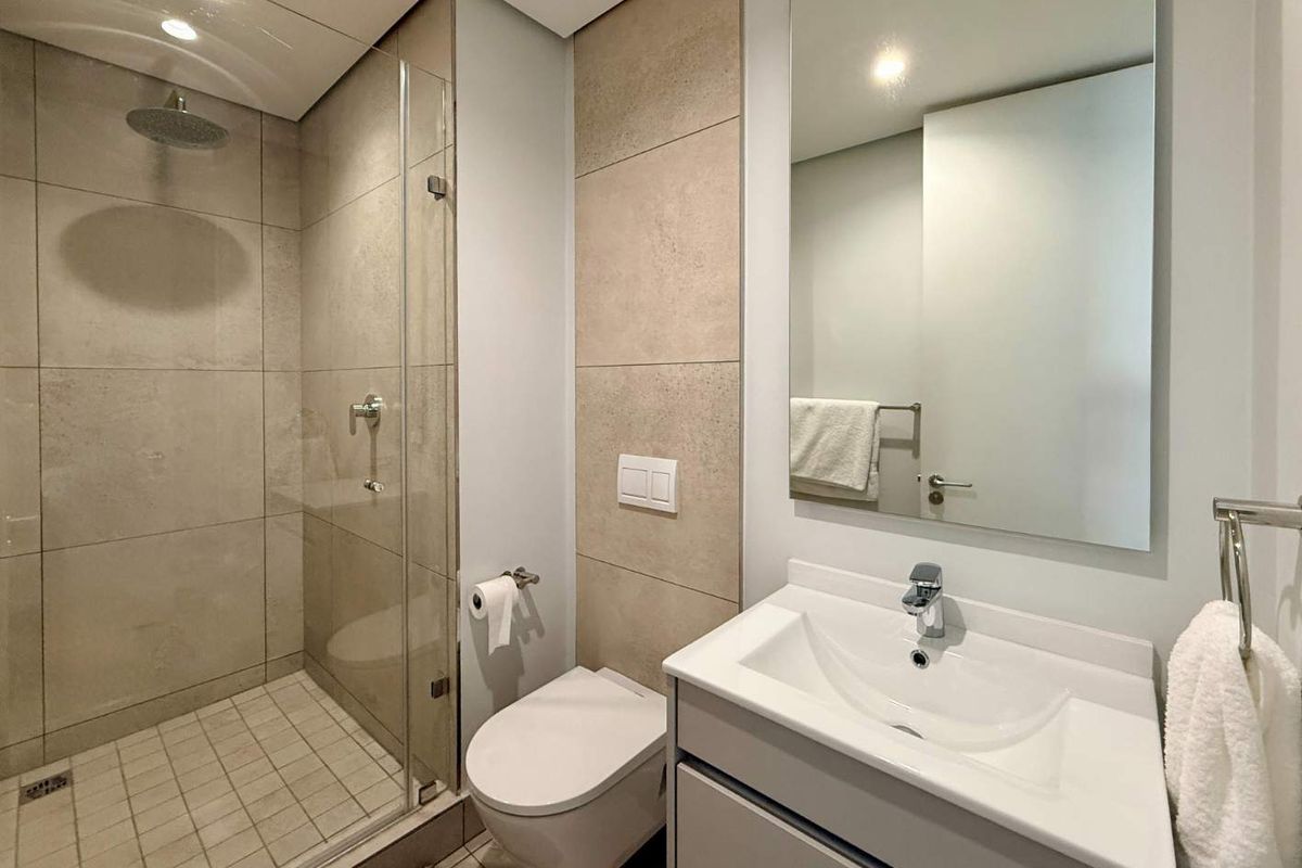 Modern bathroom featuring a walk-in shower with glass screen, wall-hung toilet, and a sleek vanity unit with basin.