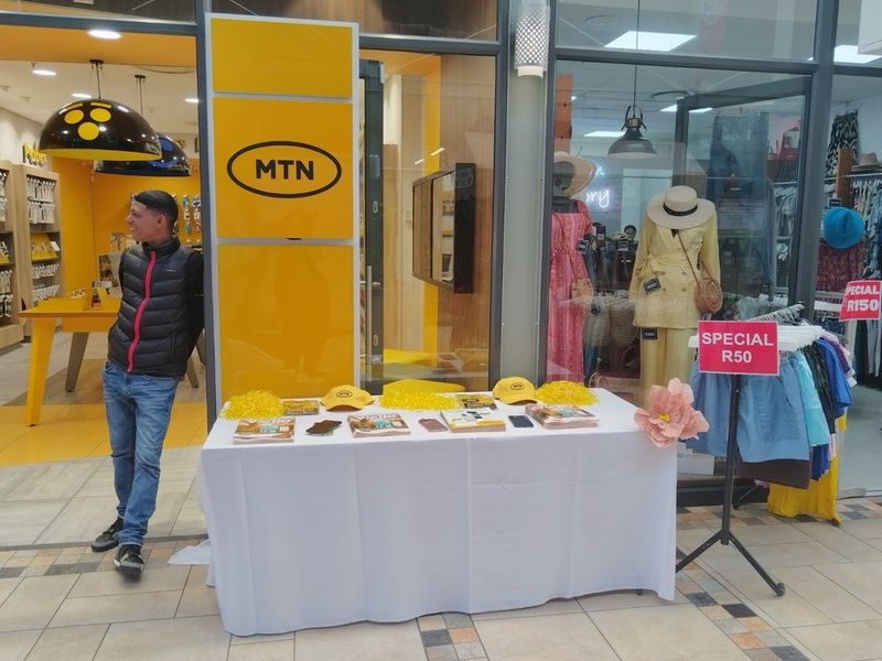 A retail storefront entrance featuring glass panels, tiled flooring, and modern recessed lighting, currently utilized for promotional display.