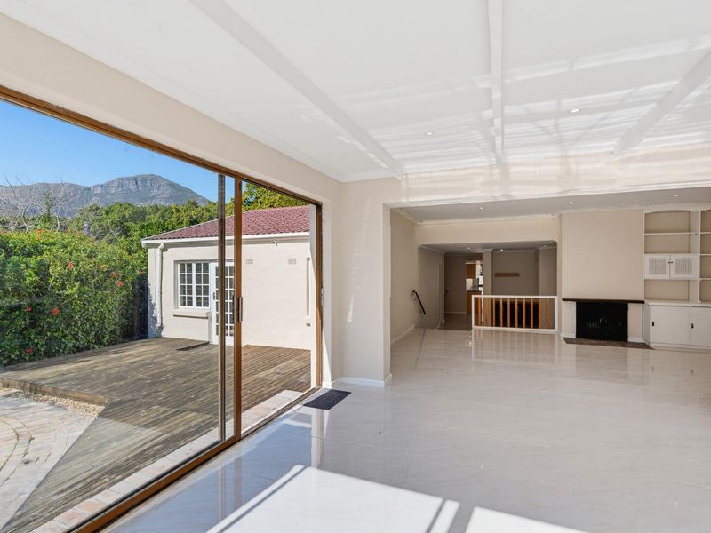 Spacious open-plan living area featuring polished tile floors, a fireplace, built-in cabinetry, and large sliding doors opening onto a wooden deck.