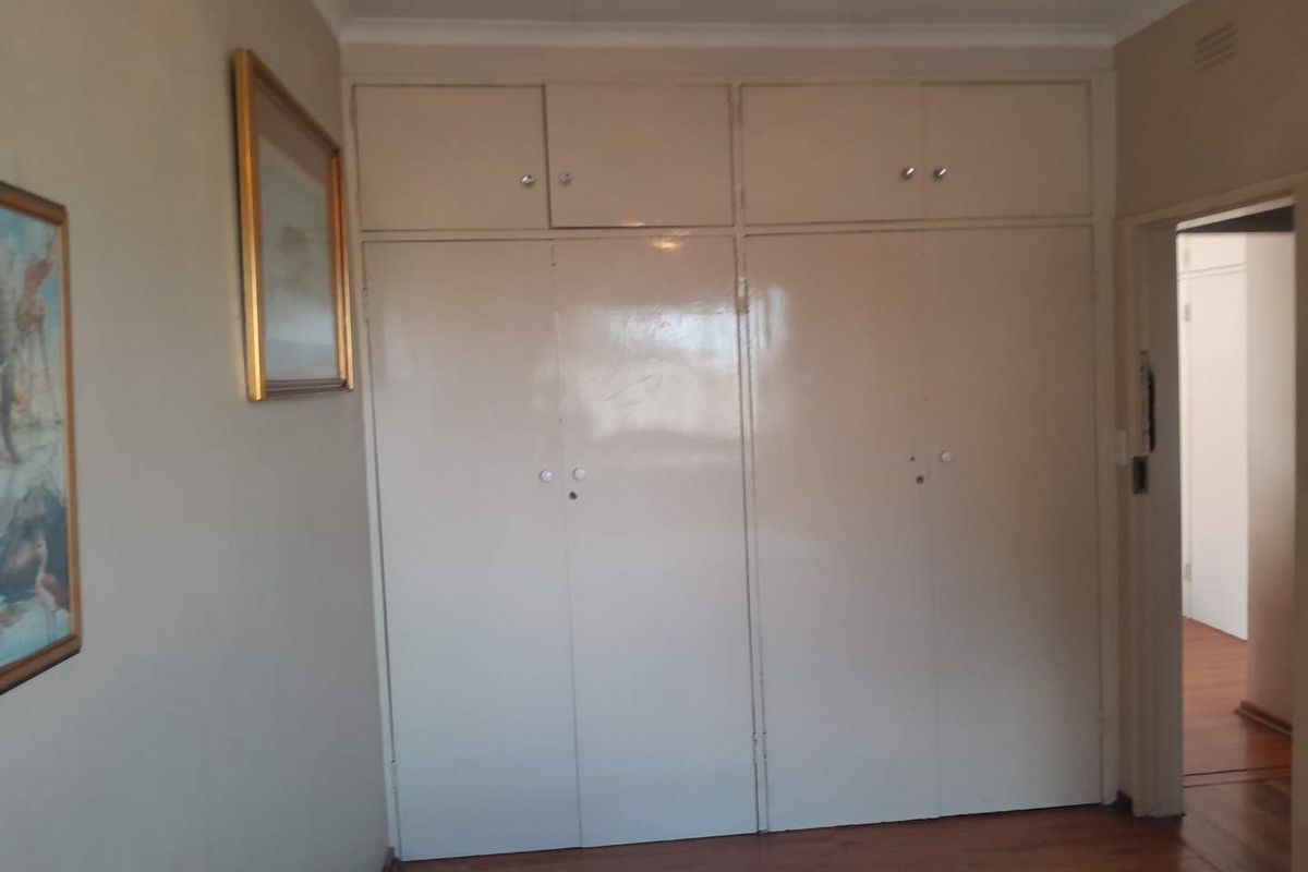 A bedroom featuring floor-to-ceiling built-in storage cupboards with overhead cabinets, providing ample integrated storage space.