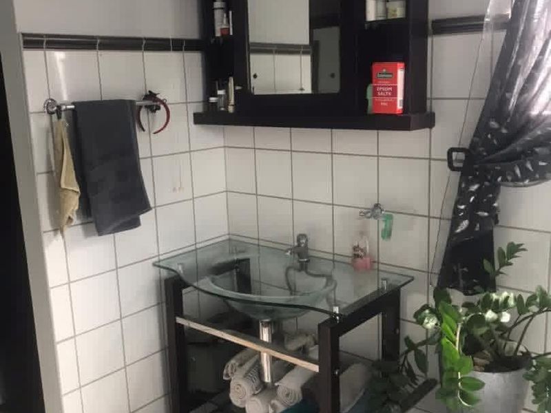 A bathroom vanity area featuring a glass vessel sink, dark wood-finish medicine cabinet, and white ceramic wall tiling.