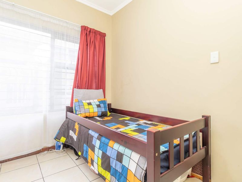 A standard bedroom featuring tiled flooring and a large window with curtain tracks.