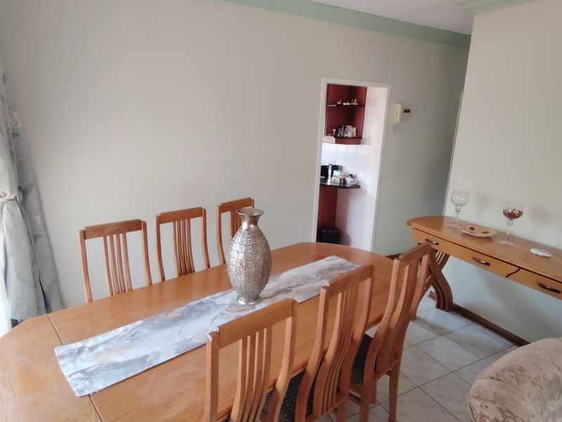 A dining room featuring tiled flooring and an archway leading to an adjacent utility or kitchen area.