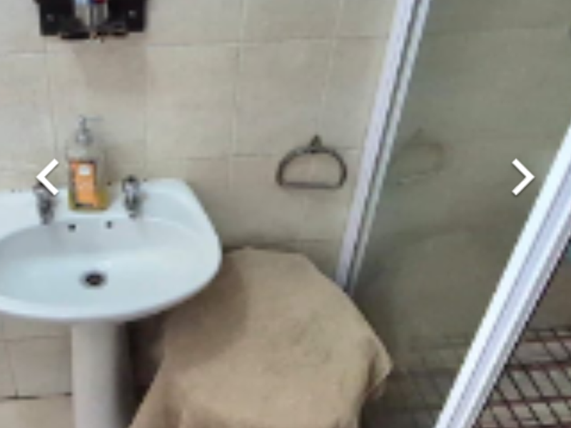 A compact bathroom featuring a pedestal basin, tiled walls, and a shower enclosure with a glass door.
