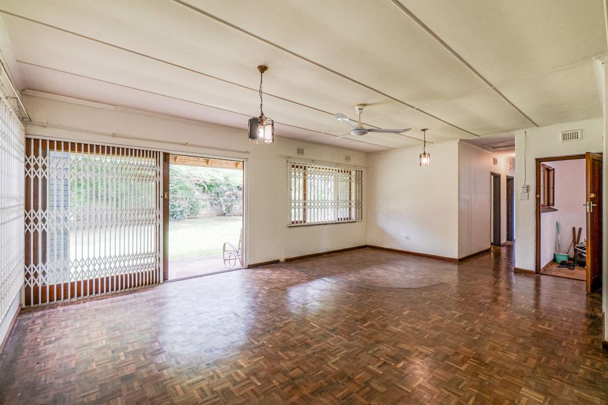 Spacious living area featuring traditional parquet flooring, ceiling fan, and sliding security gates providing direct access to the rear garden.