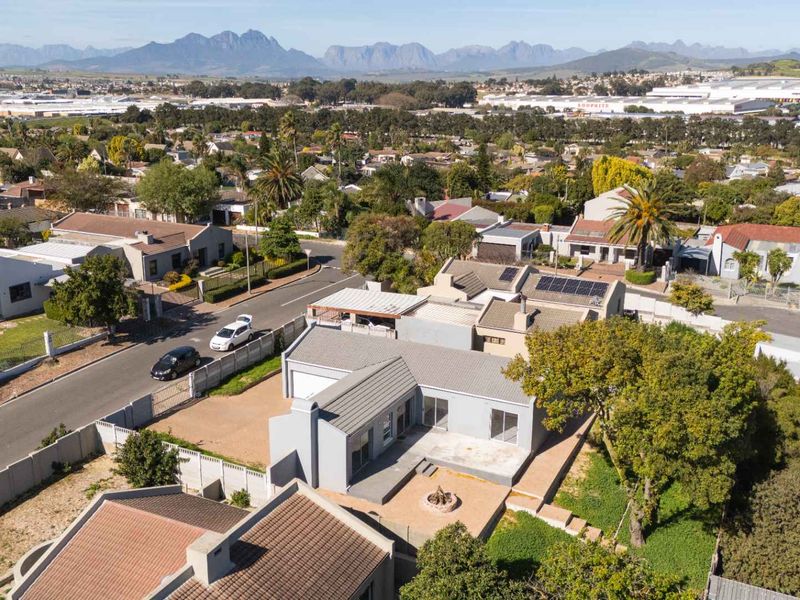 Aerial view of the property showcasing the roof structure, solar panels, rear patio area with a fire pit, and surrounding residential neighborhood.