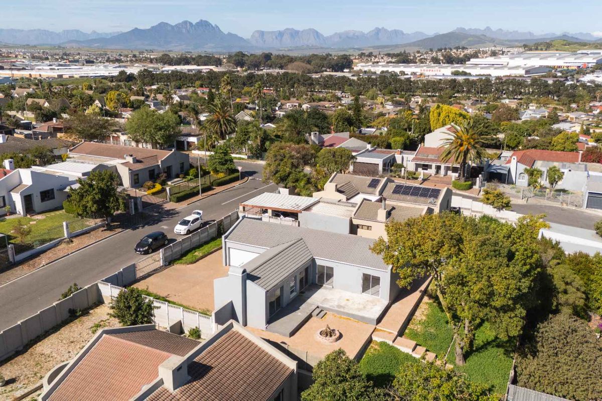 Aerial view of the property showcasing the roof structure, solar panels, rear patio area with a fire pit, and surrounding residential neighborhood.