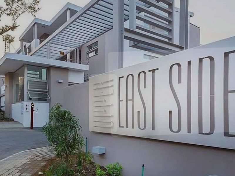 Modern apartment complex entrance featuring contemporary architectural design, clean facade lines, and prominent signage at the property boundary.