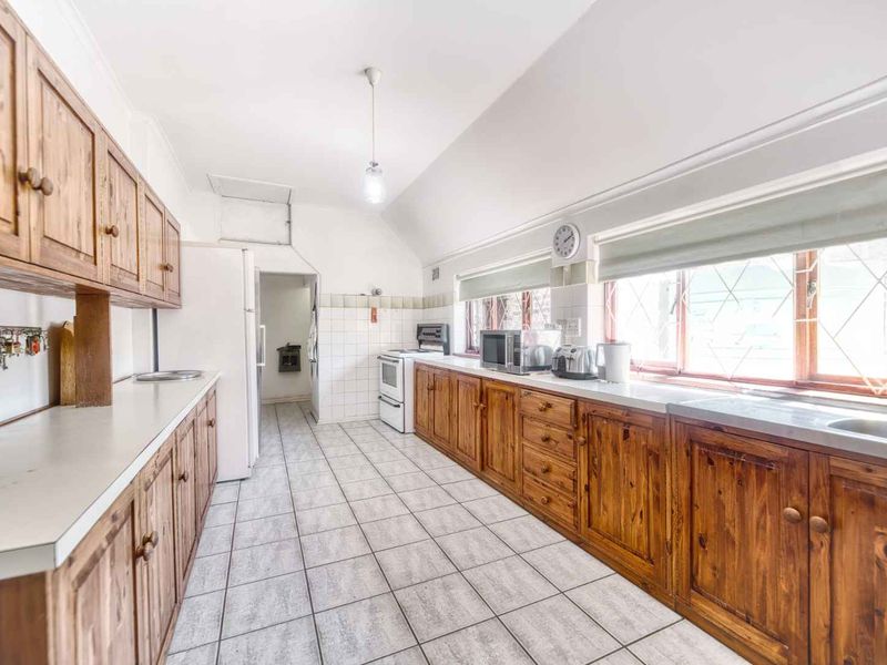 A functional kitchen featuring extensive wooden cabinetry, tiled flooring, a built-in oven, and ample counter space with a double sink.